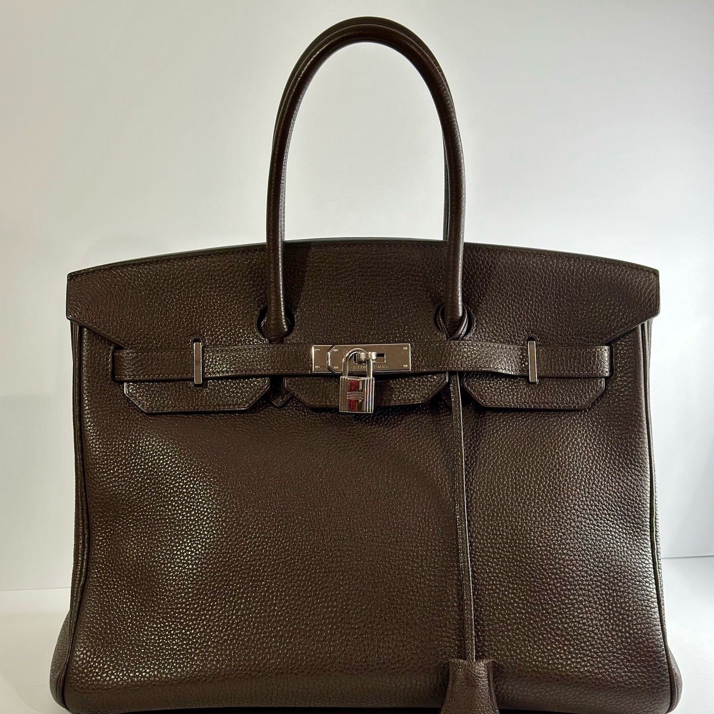 Brown leather handbag with silver hardware on a white background