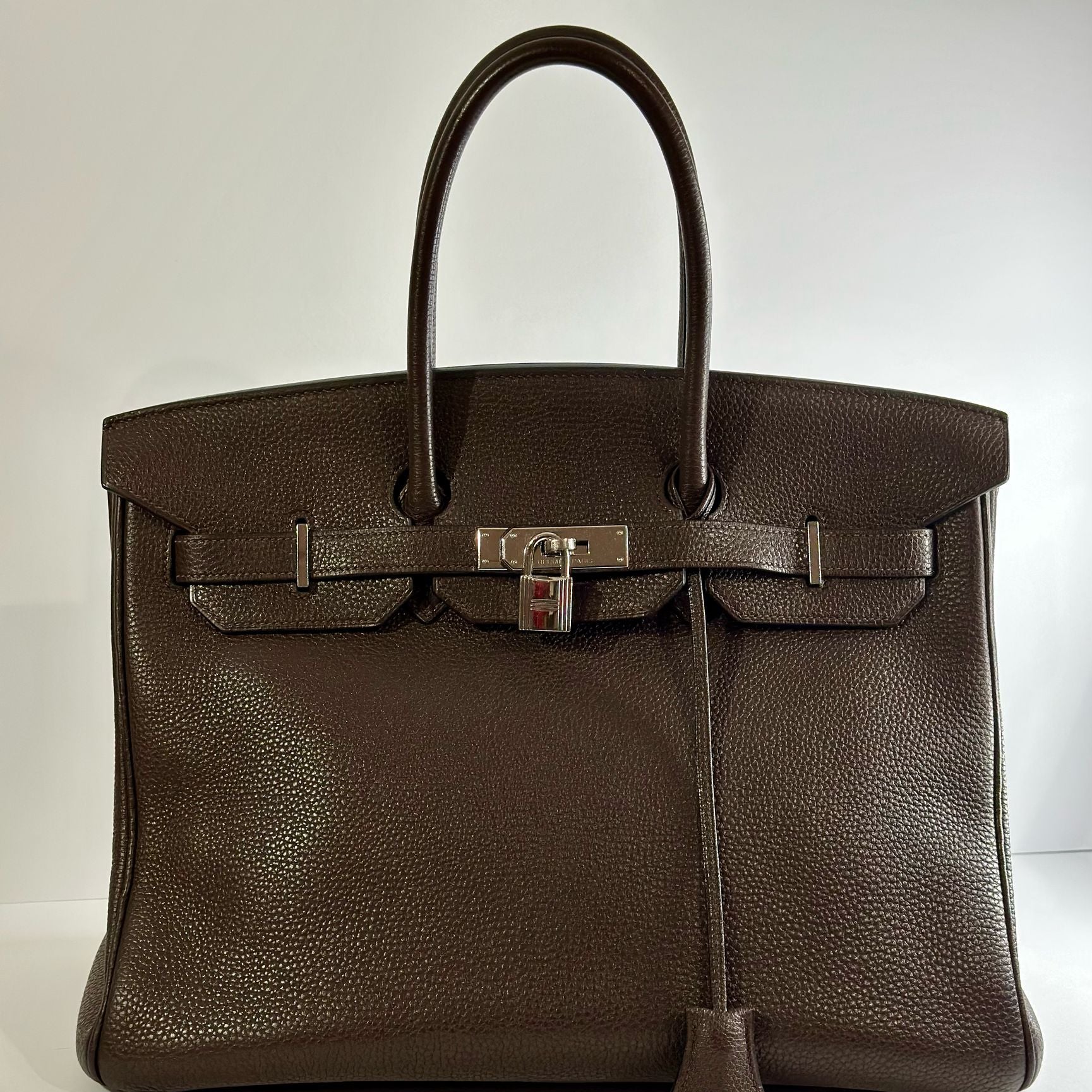 Brown leather handbag with silver hardware on a white background